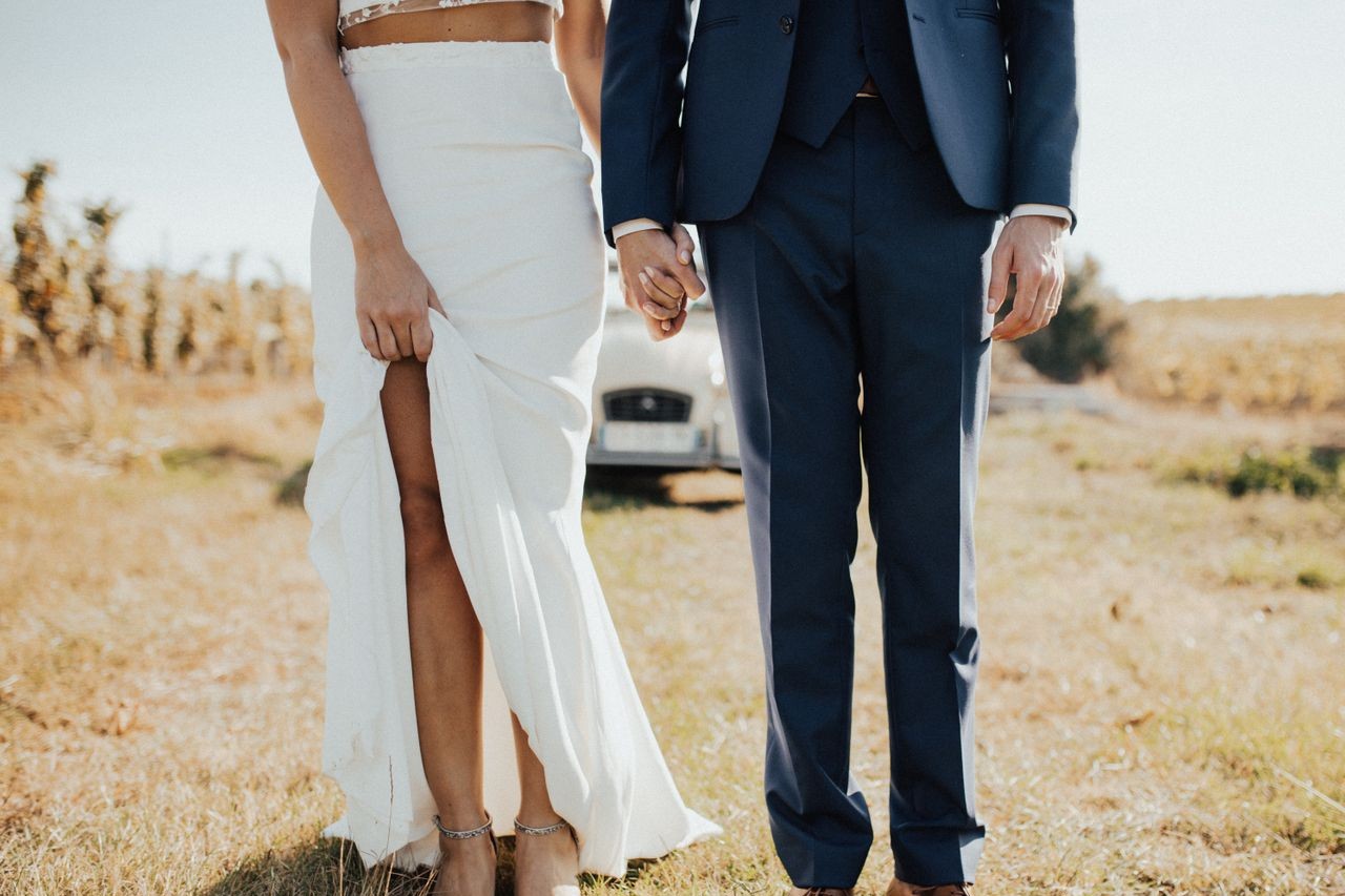 A newly wed couple stands in front of their getaway car before going to their honeymoon