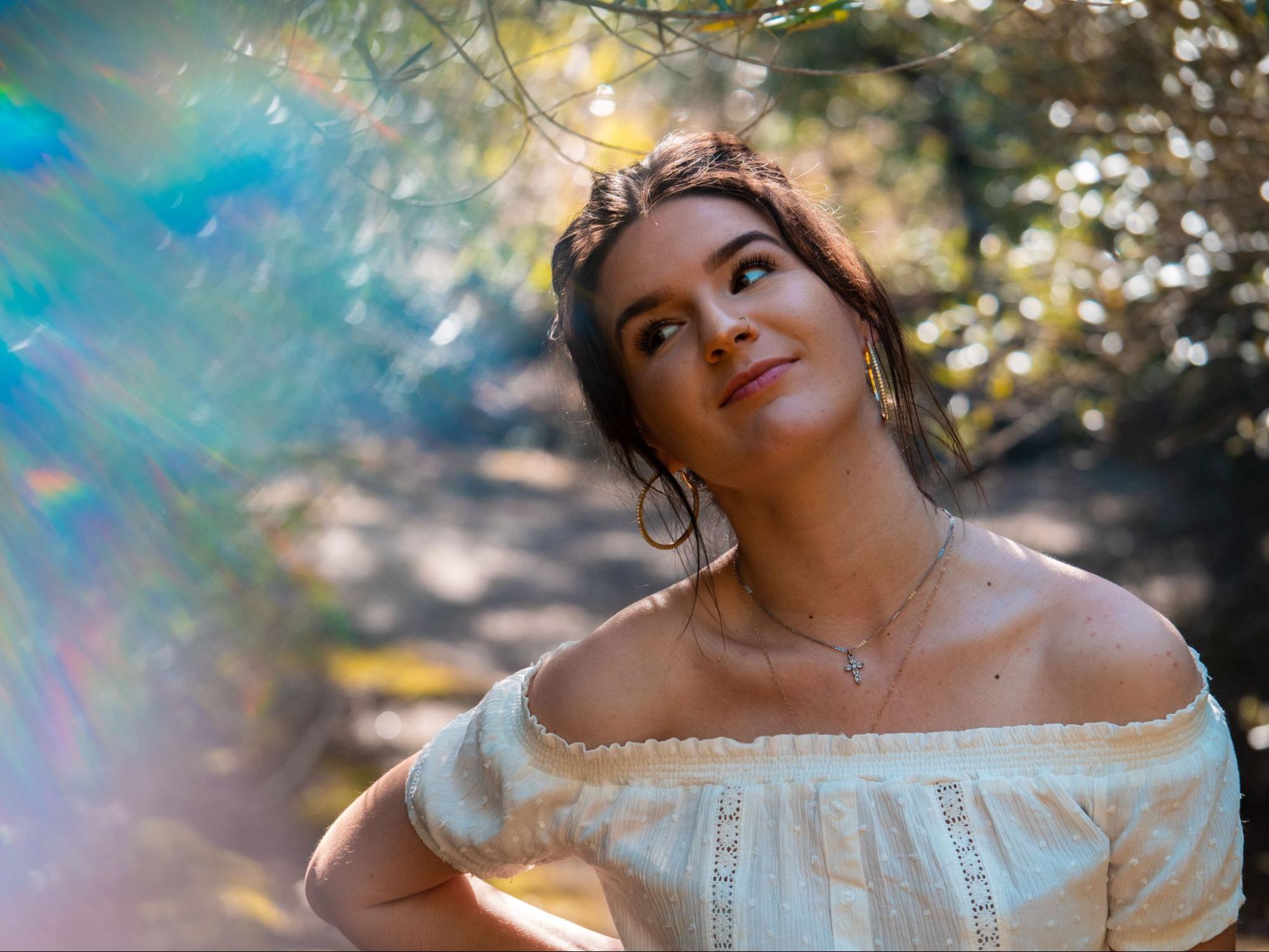 A woman wearing hoop earrings and a cross necklace explores the sunny landscapes of Napa Valley