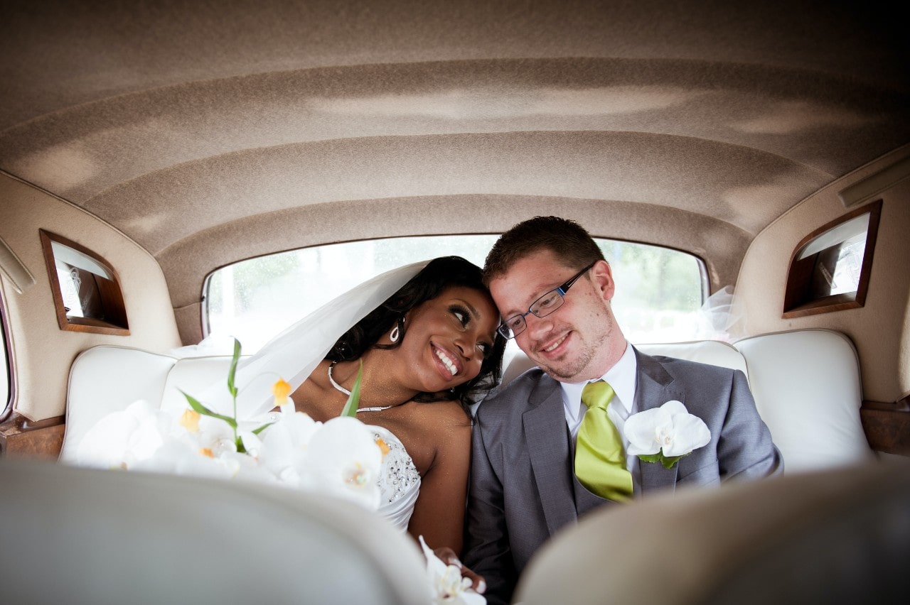 A newly-wed couple cuddles together in the back of a limo as they travel to their honeymoon destination