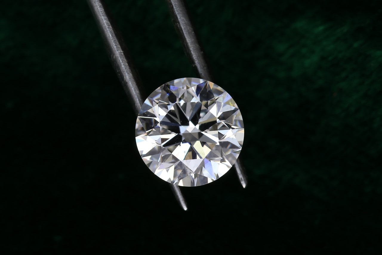 A brilliant diamond, possibly lab-grown, held with tweezers