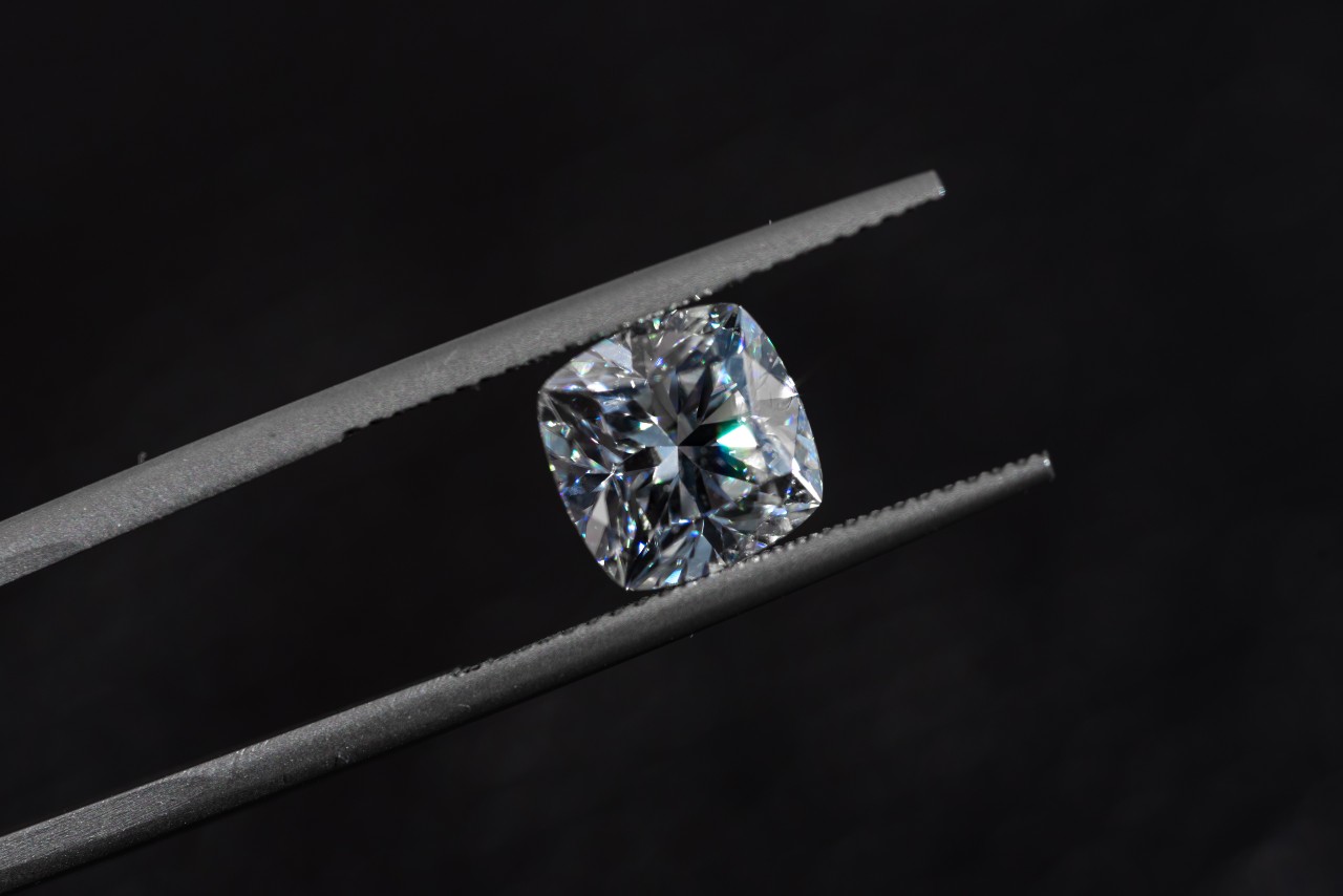 Cushion cut diamond, almost certainly a natural stone, held with tweezers