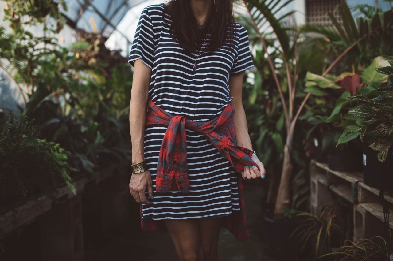 A woman wearing jewelry sports a striped t-shirt dress at a local greenhouse