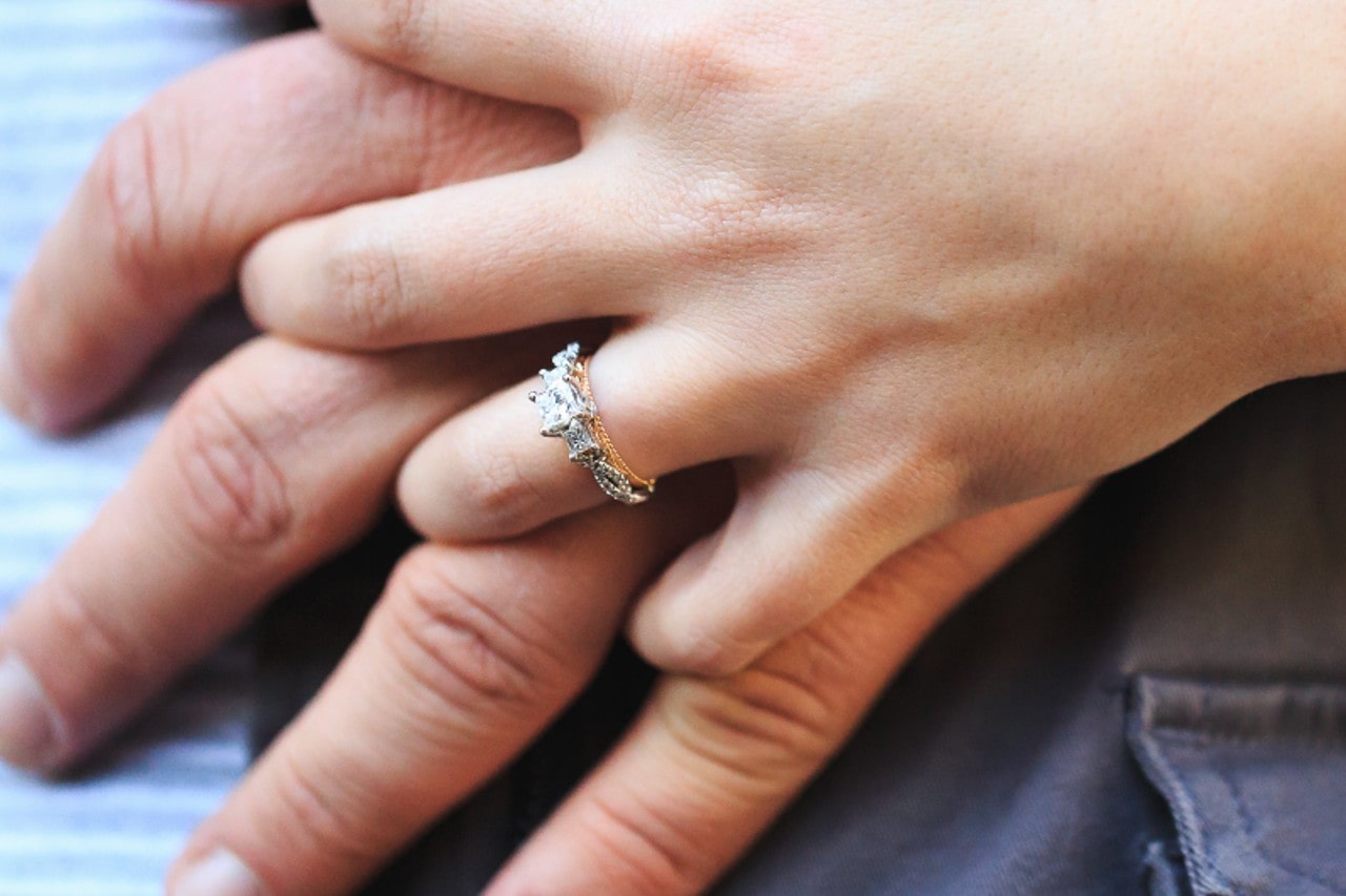 A bride-to-be holds her partner’s hand, showing off her modern engagement ring.