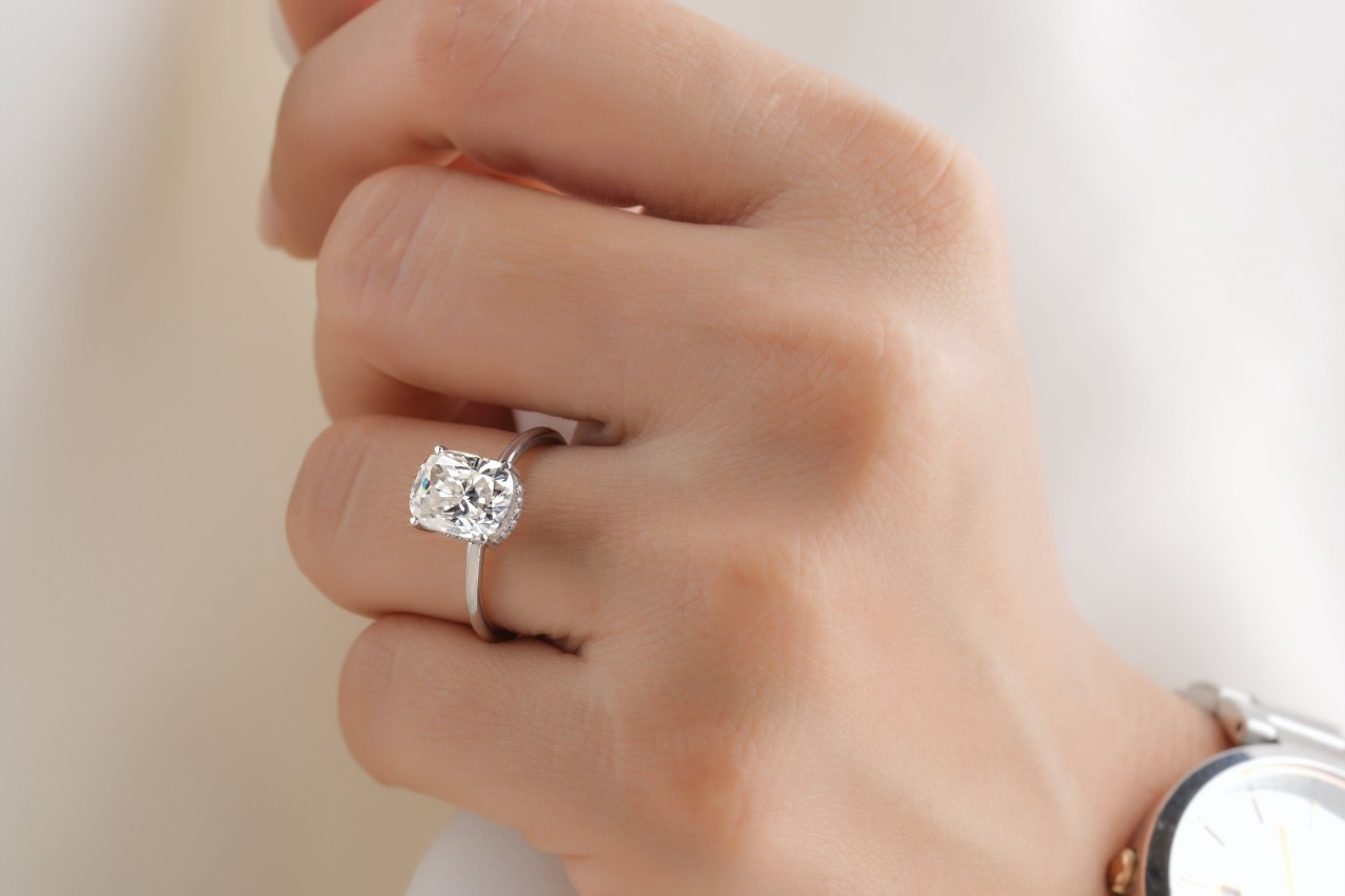 a lady’s hand wearing a platinum engagement ring and a watch