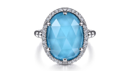 a white gold fashion ring featuring a large, oval shaped turquoise with accent diamonds surrounding it