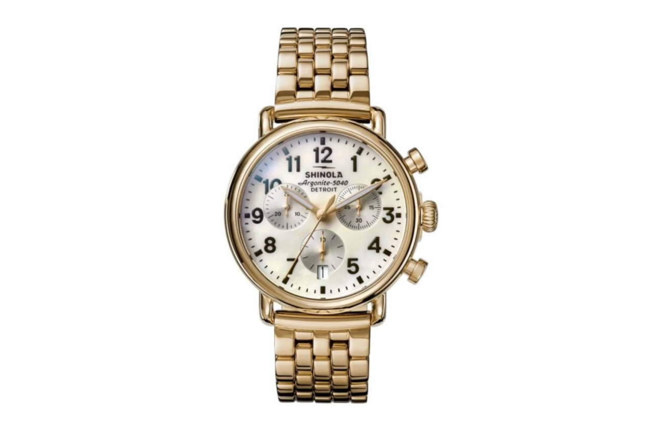 A yellow gold Shinola Runwell Chrono watch with a white dial, three subdials, and black numbers.
