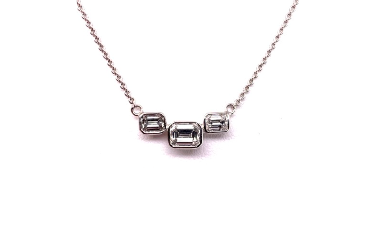 A three-stone diamond pendant necklace.