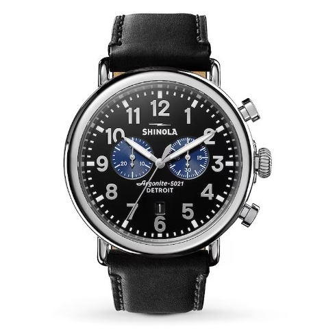 A close-up of a Shinola watch with black leather strap and a black dial with arab numerals
