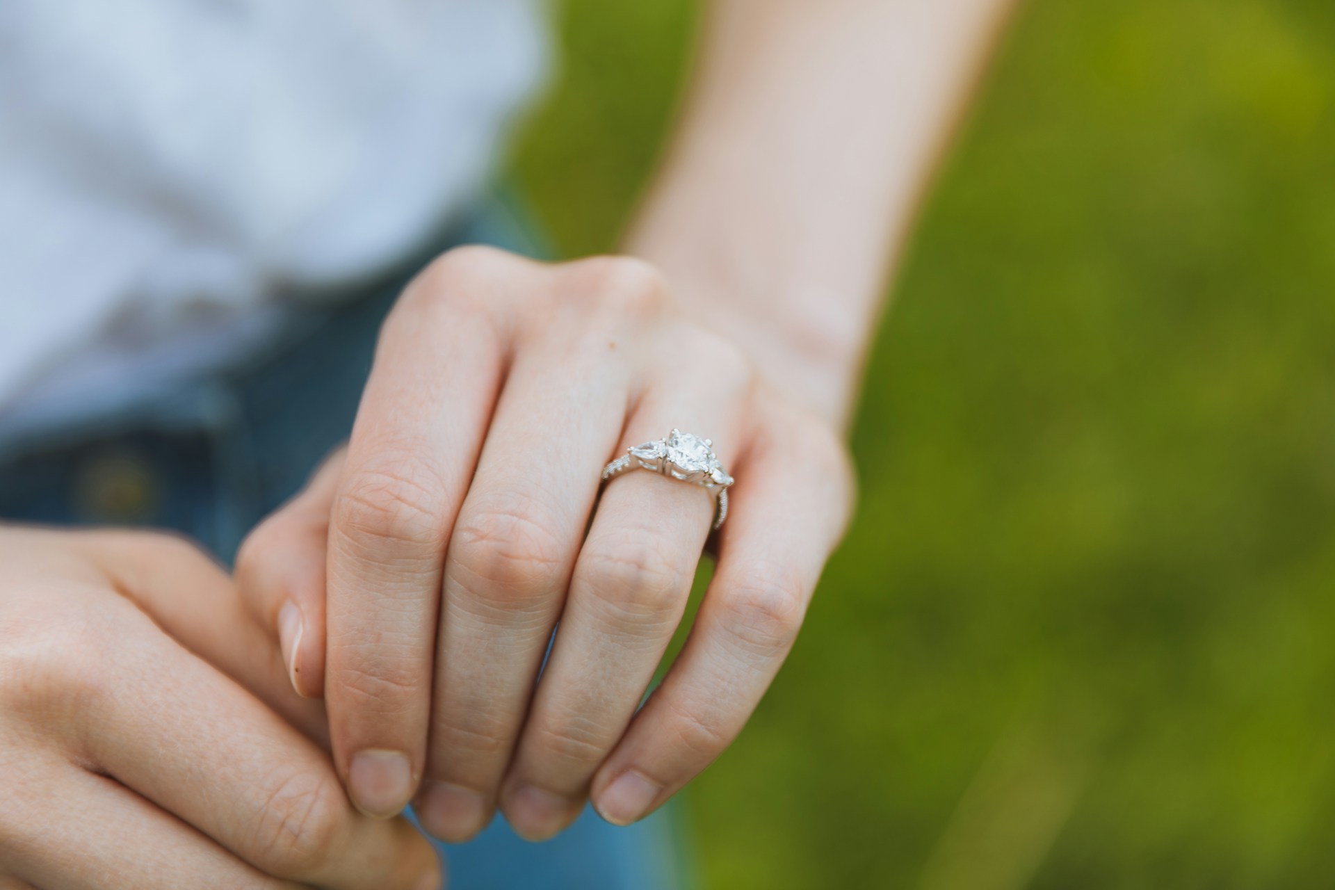 a woman’s hand adorned with a white gold, three stone engagement ring