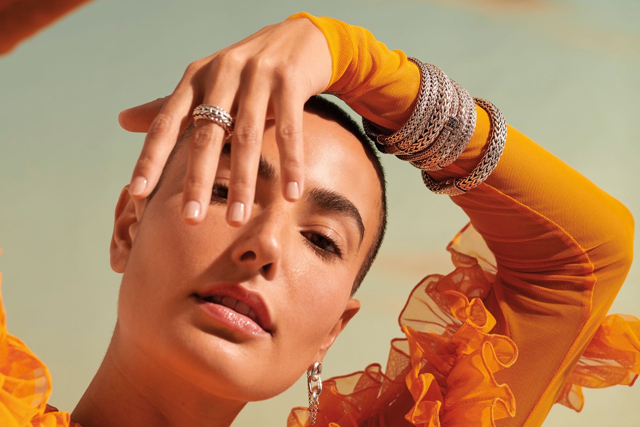 Woman wearing earrings, fashion rings, and bracelets by John Hardy