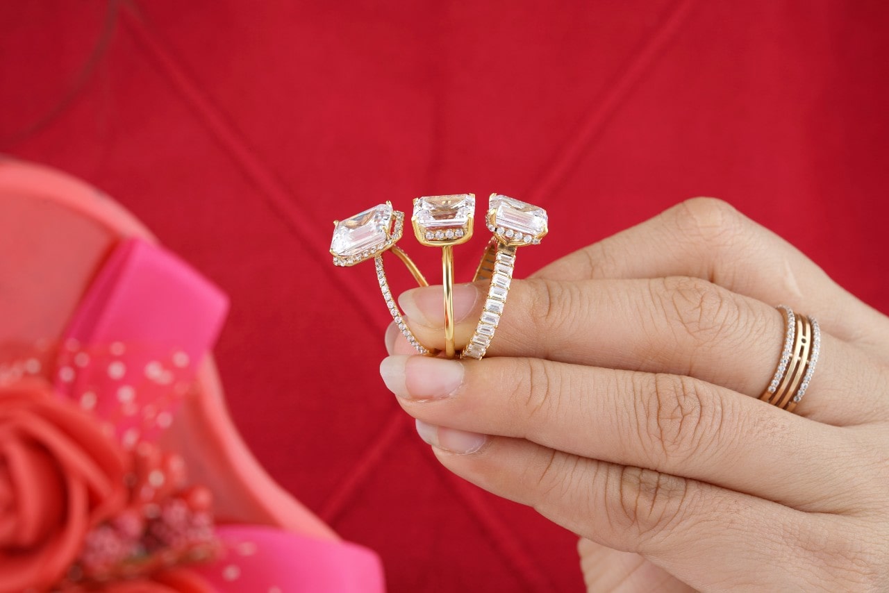 A woman compares three different styles of emerald-cut diamond engagement rings.