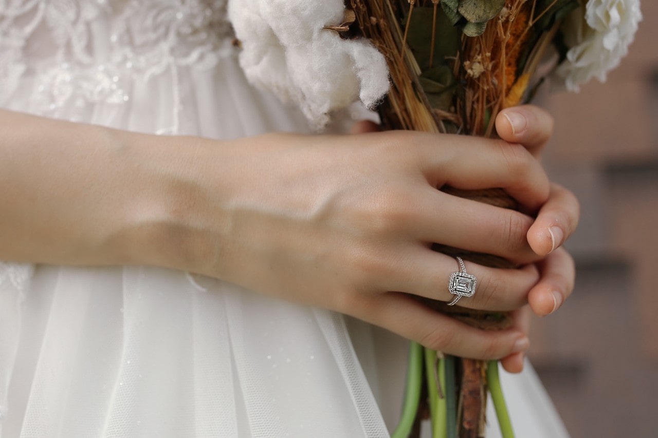 a bride holding her wedding bouquet and wearing an emerald cut engagement ring.