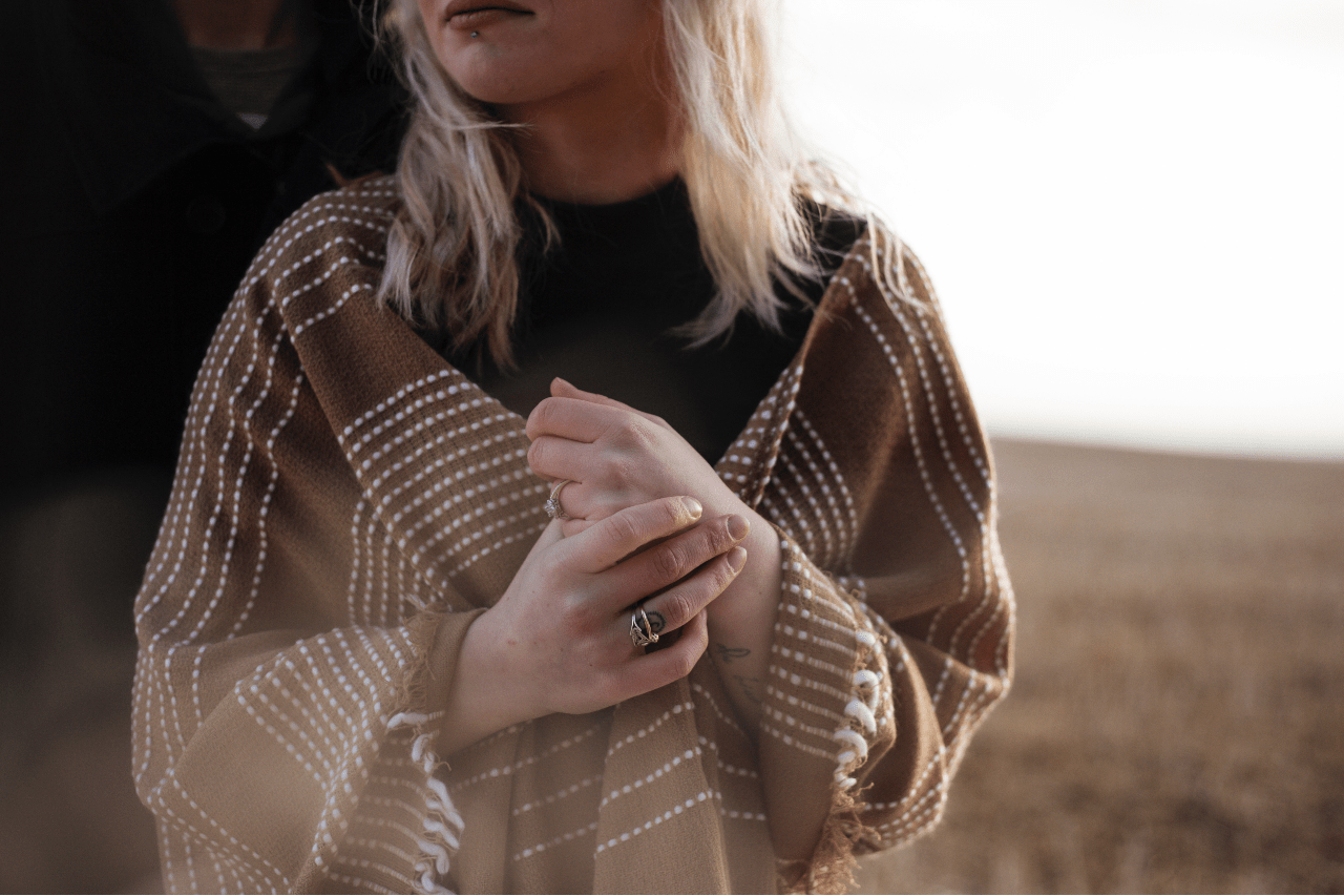 a woman in a shawl outside wears dainty fashion rings.