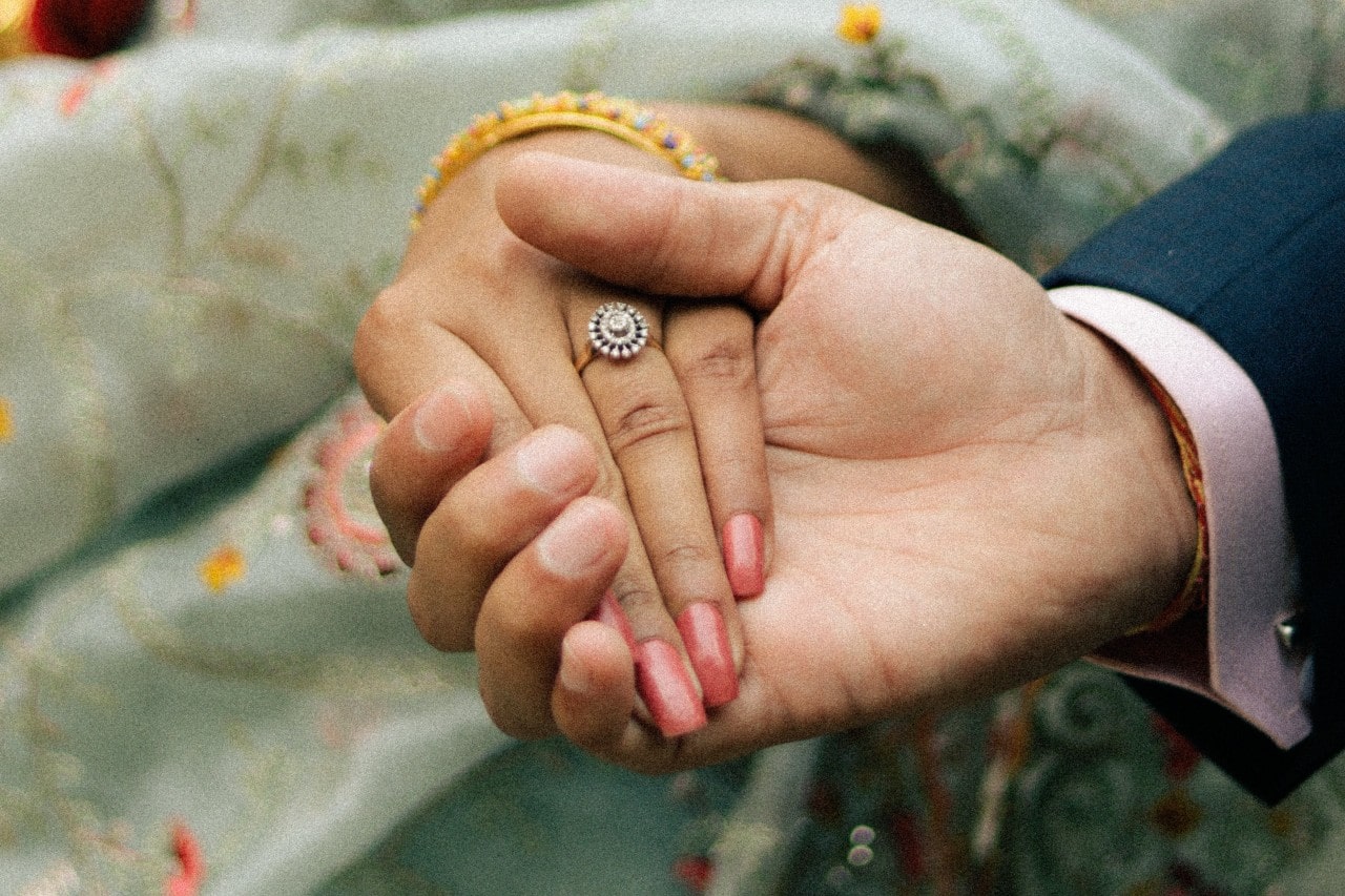a man holding a bride’s hand wearing an engagement ring