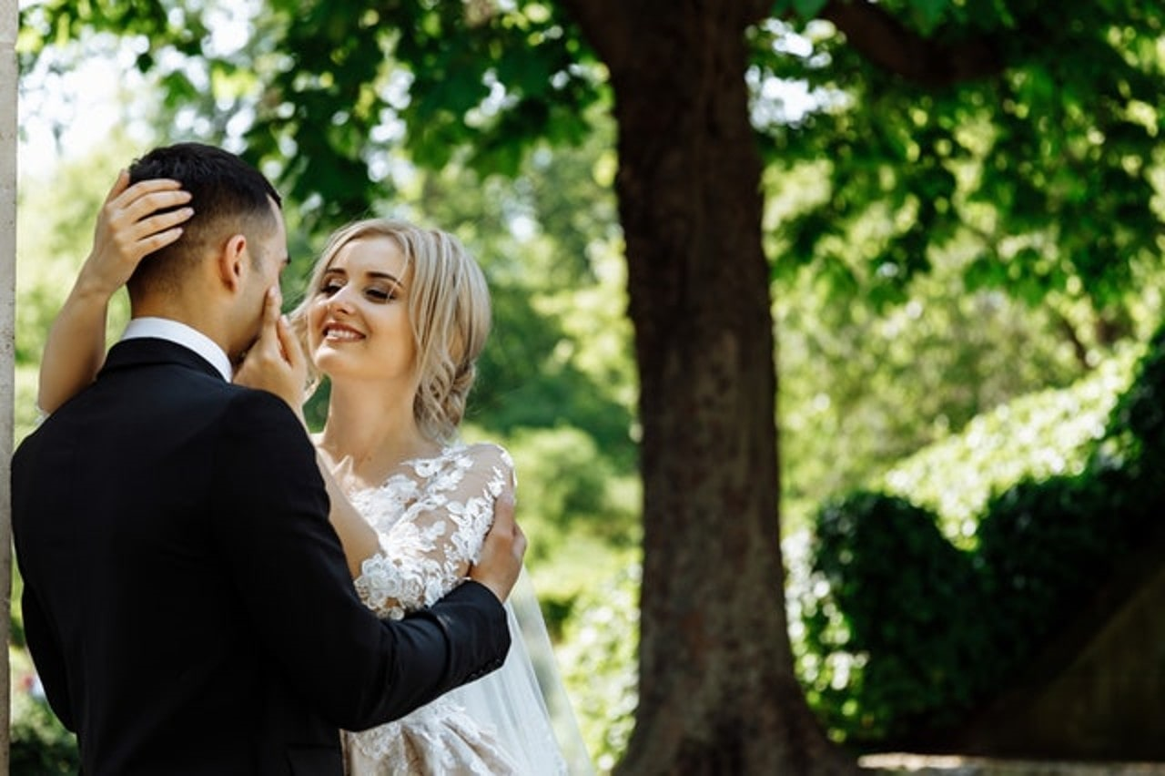 a bride and groom embracing next to a tree