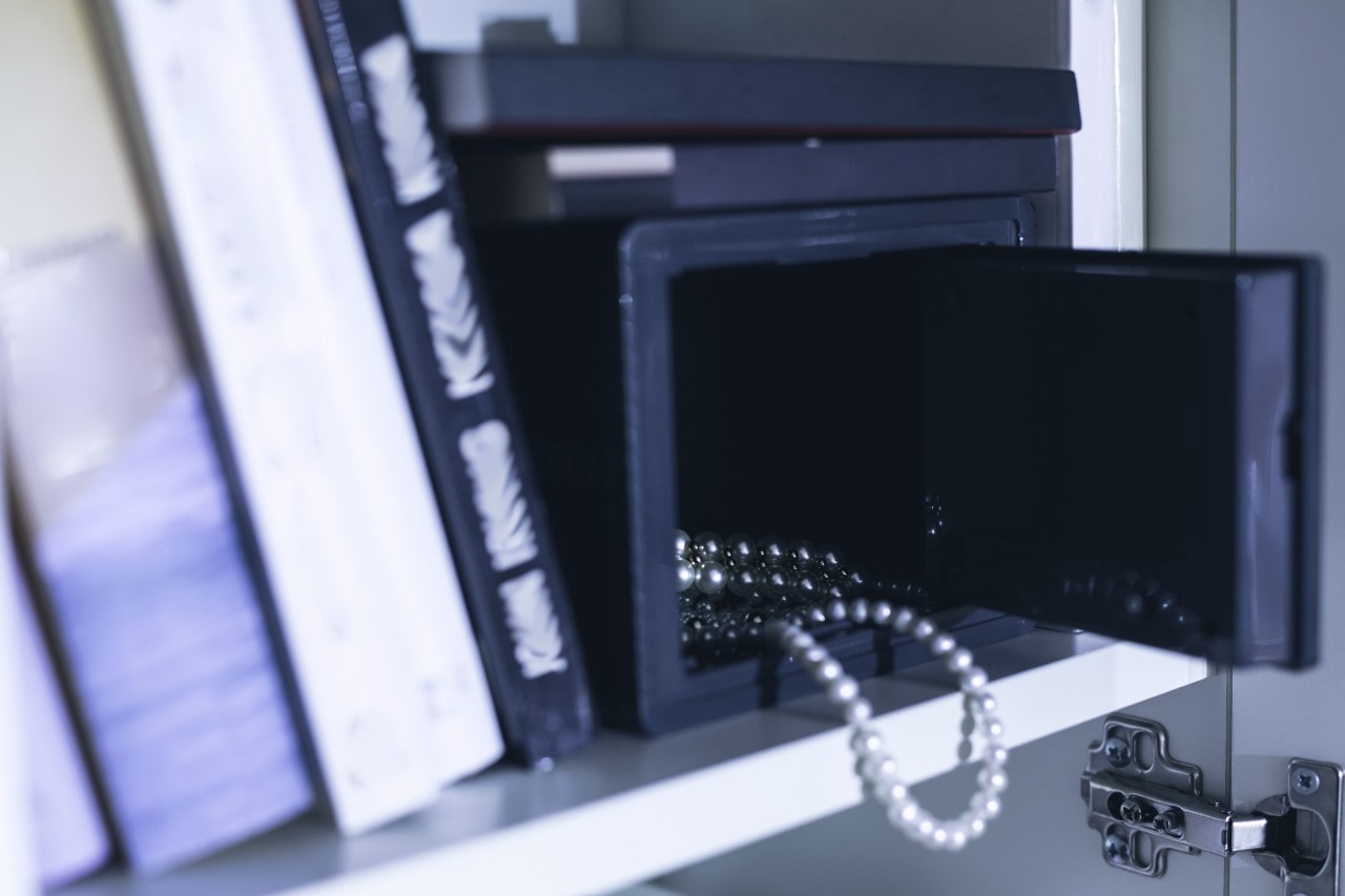 Pearls peeking out of a safe on a bookcase; protect your fine jewelry and watches further with insurance through Zillion, available at Rottermond Jewelers.
