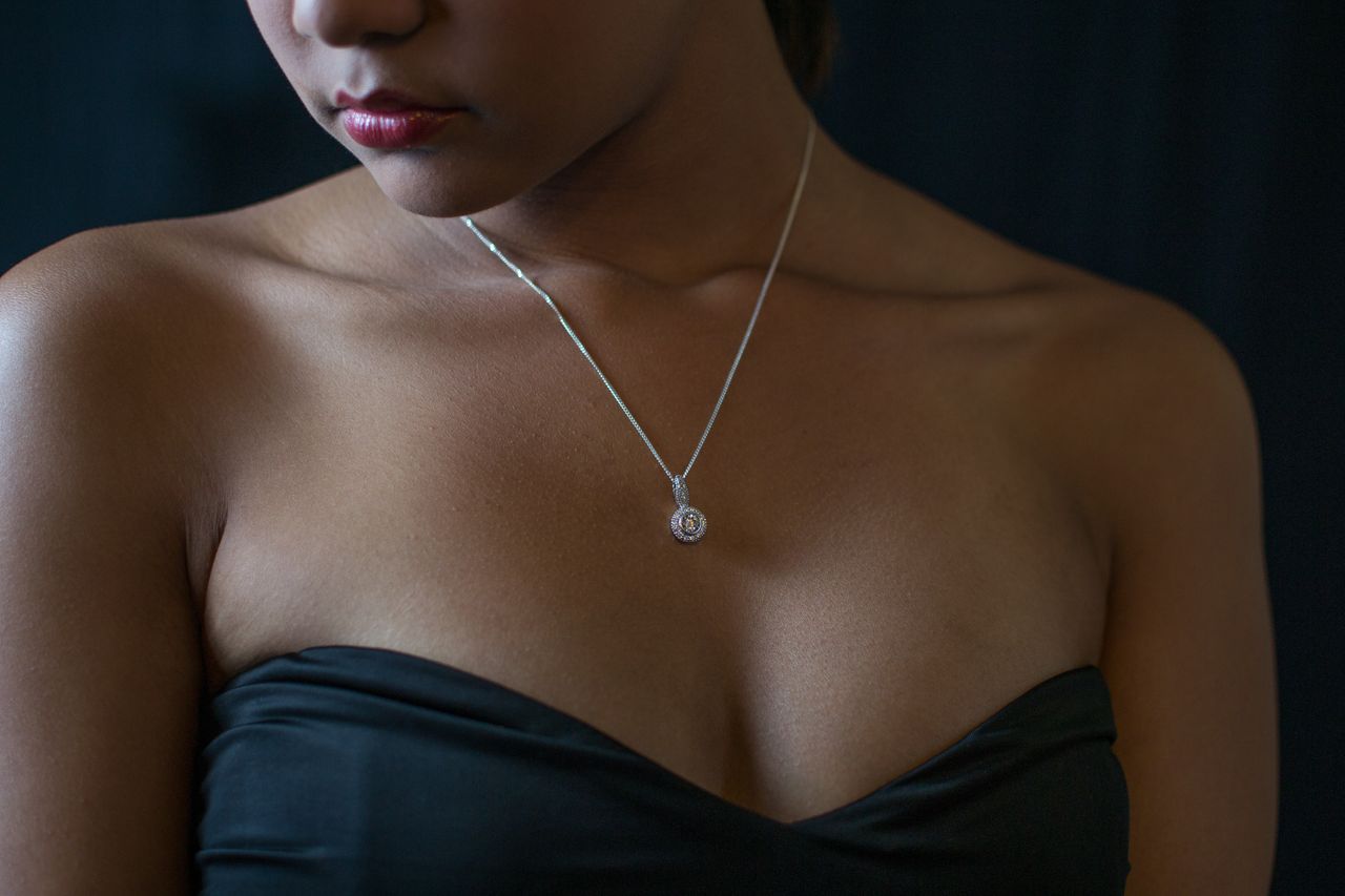 A woman in a black dress wears a solitaire diamond necklace. A woman in a black dress wears a solitaire diamond necklace.