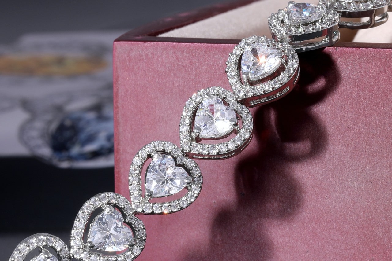 A diamond heart necklace drapes out of a jewelry box.