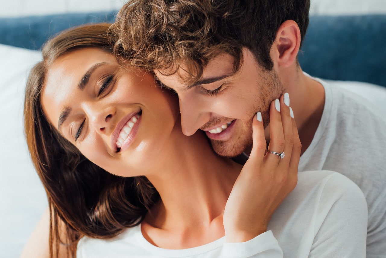 a lady wearing a designer engagement ring embracing a man