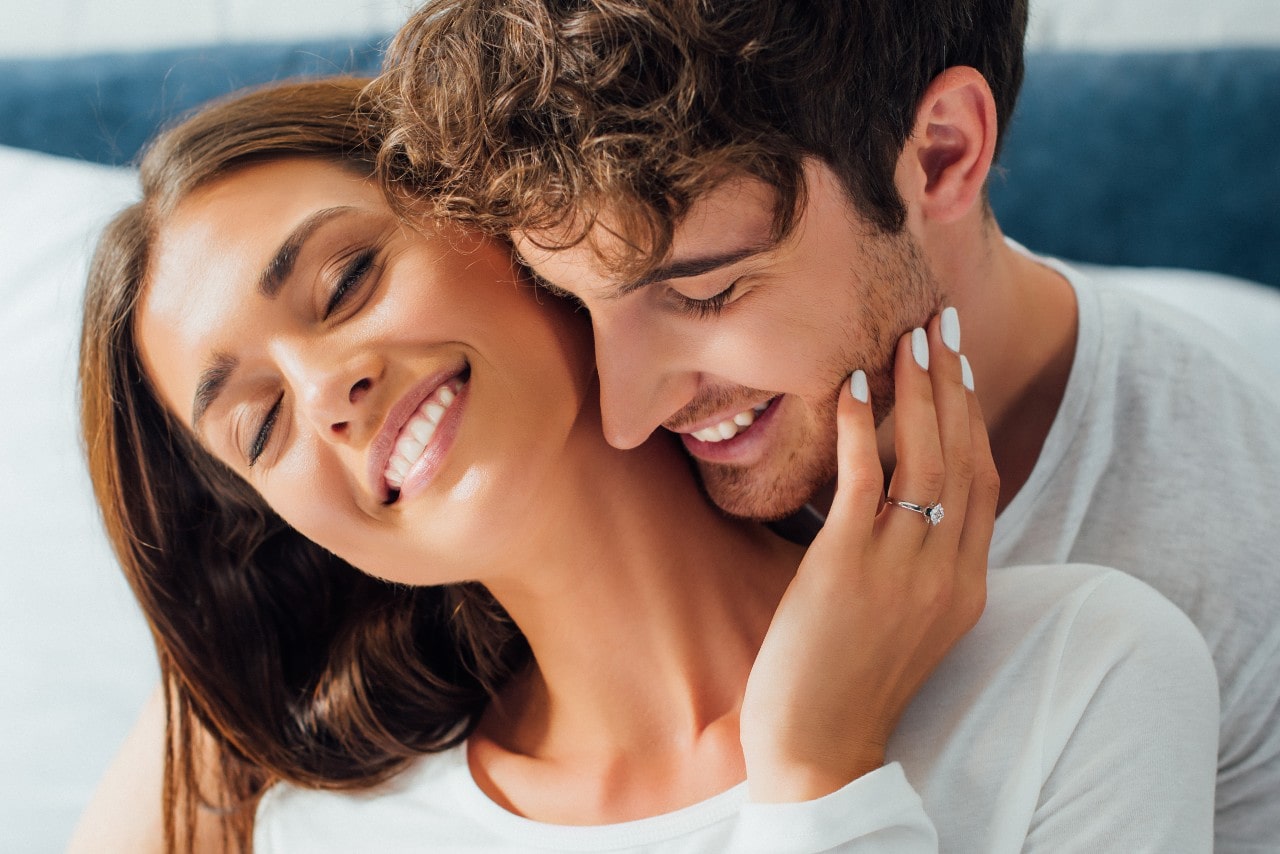 a lady wearing a designer engagement ring embracing a man a lady wearing a designer engagement ring embracing a man
