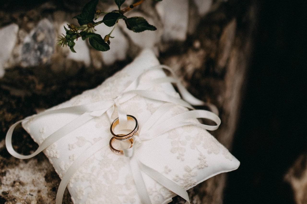 a matching set of wedding bands tied with ribbon on a white pillow a matching set of wedding bands tied with ribbon on a white pillow