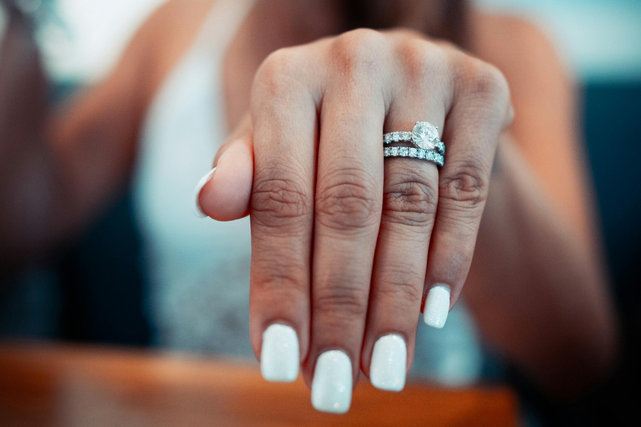 a woman’s extended hand, showing off a matching engagement ring and wedding band set a woman’s extended hand, showing off a matching engagement ring and wedding band set