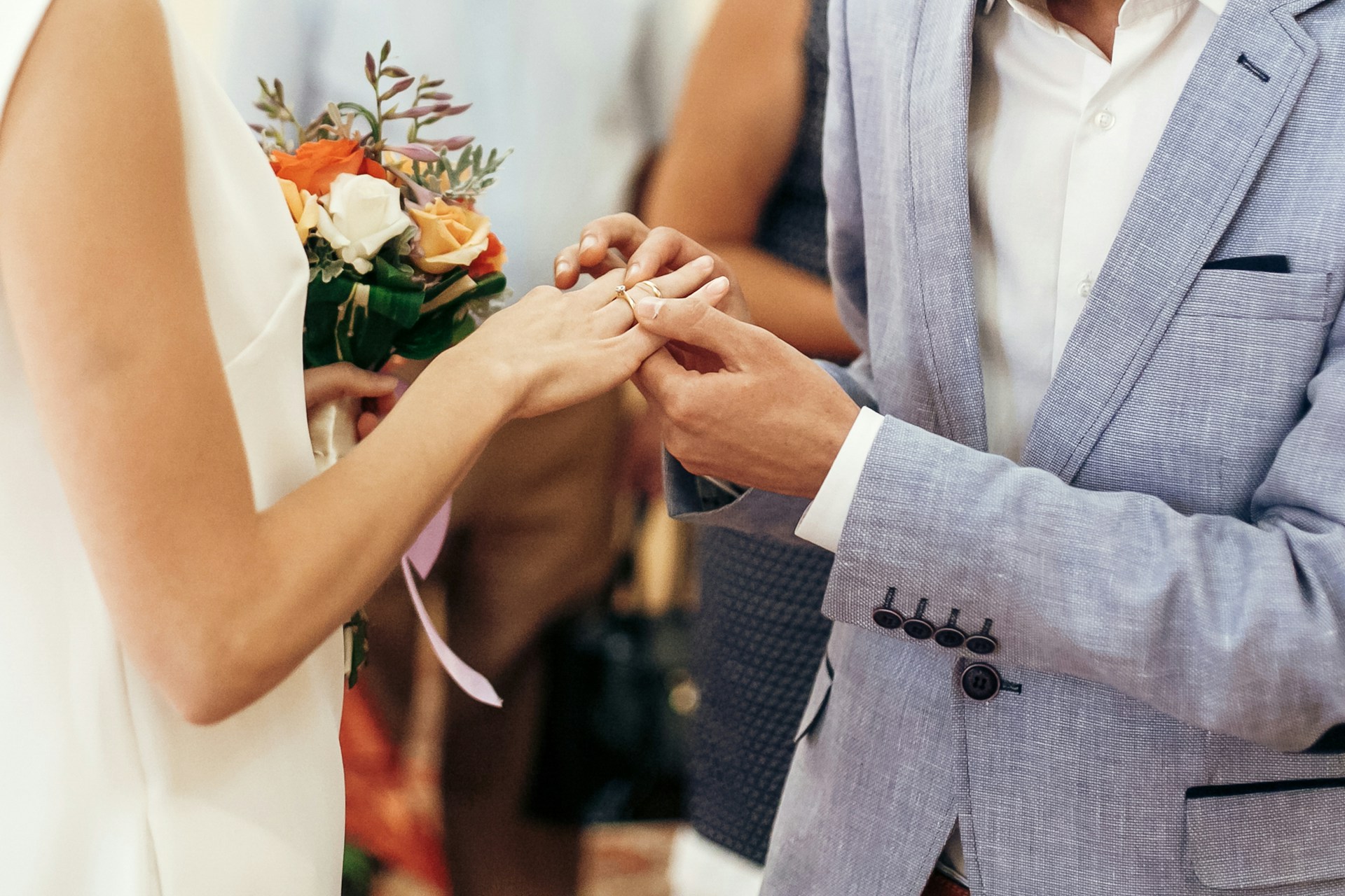 A close-up of a groom slipping a wedding band on his bride’s finger. A close-up of a groom slipping a wedding band on his bride’s finger.